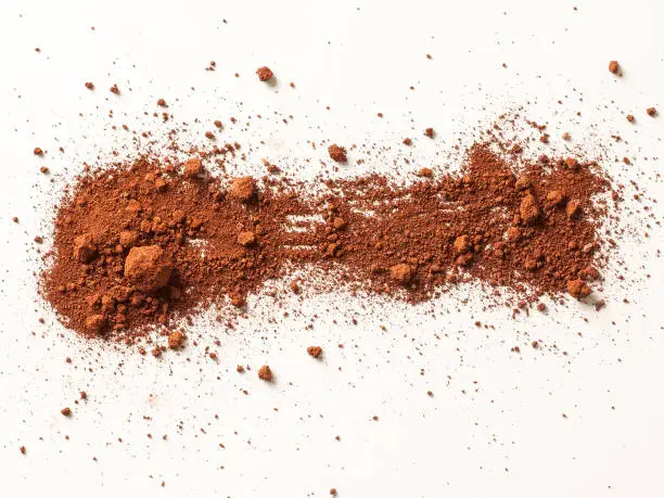 Saturated, clumpy Oklahoma red clay soil scattered on a white surface, illustrating the problematic nature of the fine dirt that can cause plumbing damage across Oklahoma City.