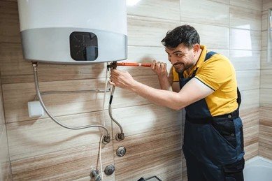 Plumber in Oklahoma City adjusting water heater pipe valves to flush sediment.