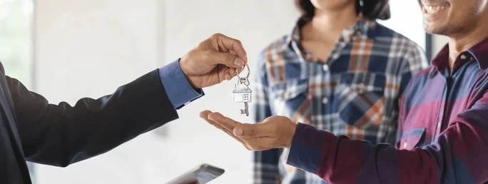 Landlord handing house keys to a tenant over blog post titled Landlord vs Tenant Plumbing Responsibilities Under Oklahoma Law.