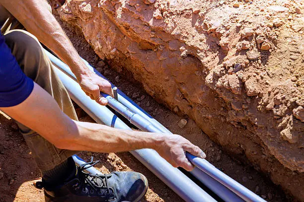 Plumber inspecting an underground main water service line pipe in Oklahoma City.