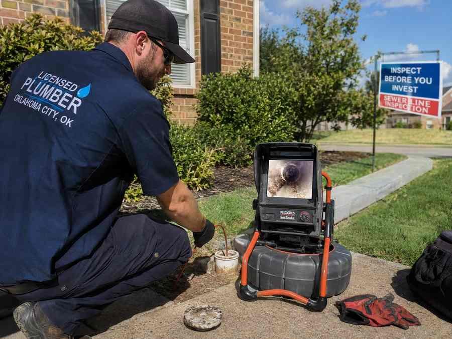 Plumber performing a sewer camera inspection through an outdoor cleanout at a residential property in Oklahoma City.