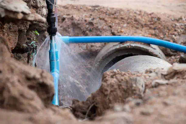 Underground pipe spraying water during trenchless sewer line repair in Oklahoma City.