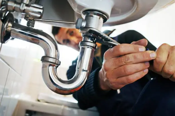 Local plumber inspecting residential water pipes and plumbing connections.