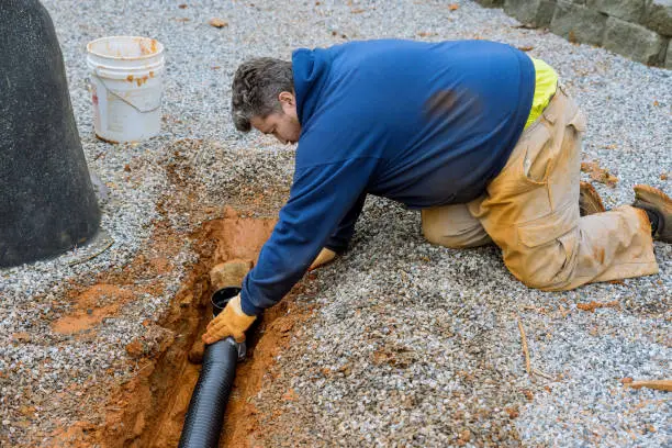 Plumber working on trenchless sewer line repair in an access hole.