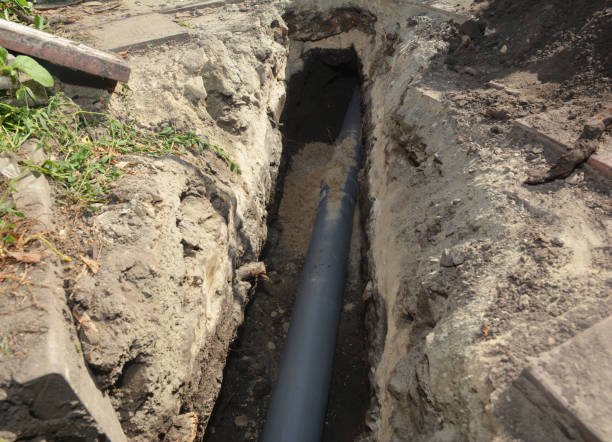 Main city sewer pipe line exposed inside a deep underground dirt trench in Oklahoma City.
